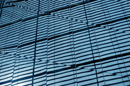 Fluctuating shades reflected on blue glass panelsの写真素材