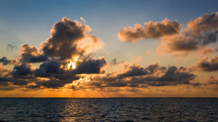 The German wadden sea at high tide during sundown. The sunlight is casting light rays through the clouds. On the horizon east friesian islands are visible. The German wadden sea is a national park and natural reserve since 1985/1986. It is also a famous travel destination in Germany and Lower Saxony.の写真素材