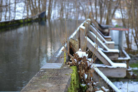 close up in winter of twigs and branches in front of a wooden water wheel with wooden water intakeの写真素材