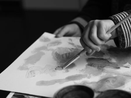 A child paints a picture with a brush and watercolor, blackandwhite picture part 2の写真素材