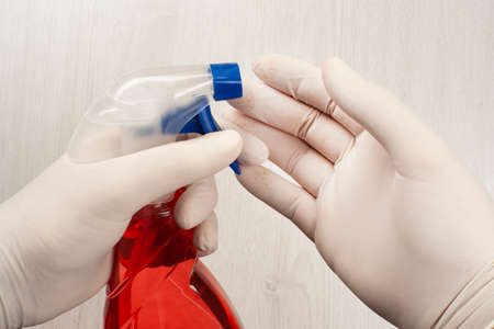 Two hands of man with glov ... or sanitizing surfaces