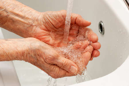 An old man washing his hands with waterの写真素材