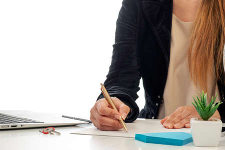 A businesswoman at the desk who is writing with a golden pen