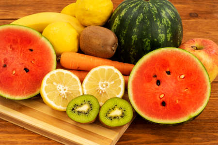 Kiwi lemons and sliced ââwatermelons on a brown wooden tableの写真素材