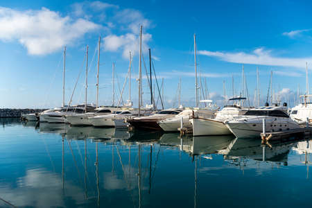Marina with yachts and boats reflected on the waterの写真素材