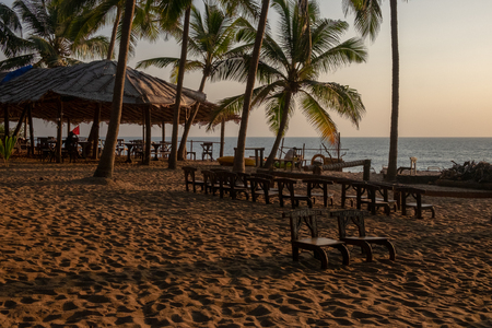 An empty wooden bar wih small chairs on the beach at sunsetの写真素材