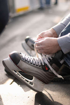 Tying laces of ice hockey skates at skating rinkの写真素材