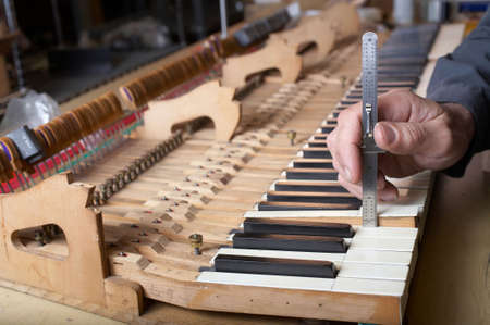 Piano technician at work checking key, DOF focus on hand