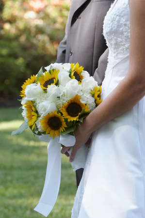 Bride holding wedding bouquet flowers against dressの写真素材