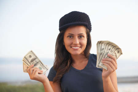 Beautiful happy young woman holding money in hands focus on face