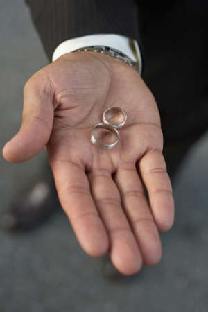 African-American hand holding silver wedding bands DOF focus on ringsの写真素材
