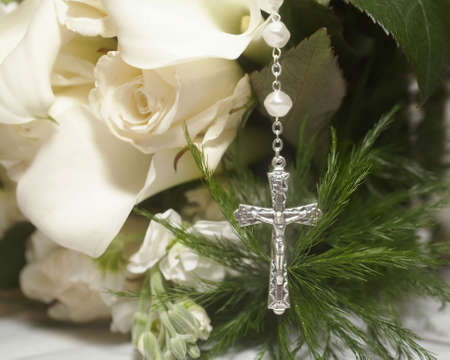 Silver cross on wedding bouquet of white rosesの写真素材