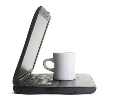 Cup of coffee on modern laptop computer