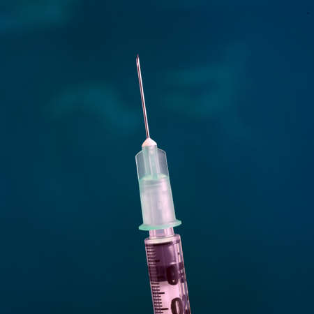 Closeup of medical syringe on blue backgroundの写真素材