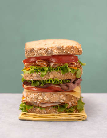 Stacked deli sandwich with fresh turkey, roast beef, tomato, lettuce, and cheeseの写真素材