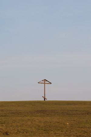 single wooden cross standing on a grassy hillの写真素材