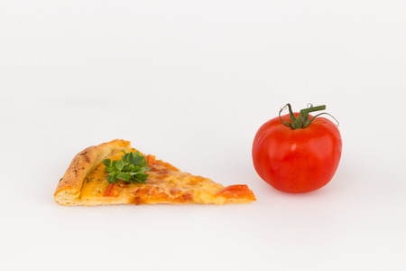 slice of pizza with basil and red tomato on a white backgroundの写真素材
