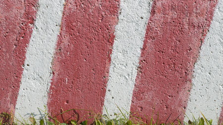 concrete painted red and white stripes and green grass at the bottom ofの写真素材