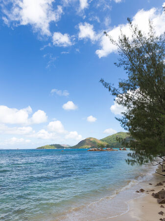 shore blue sea and green mountains in the distanceの写真素材