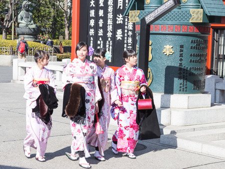 Tokyo - February 4, 2015: Four girls in the Japanese national dress near the temple and Buddha statue in the background February 4, 2015, Tokyo, Japanのeditorial素材