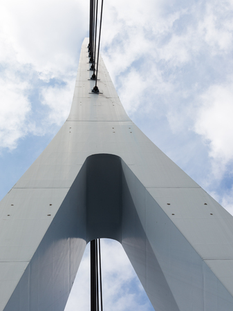 gray painted metal bridge support against a blue sky with cloudsの写真素材