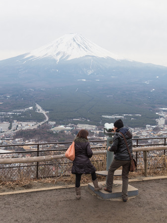 surrounding Tokyo - January 29, 2015: Young man and woman with shopping bags looking through binoculars at the city at the foot of the volcano Fuji January 29, 2015, the surrounding area of Tokyo, Japanのeditorial素材