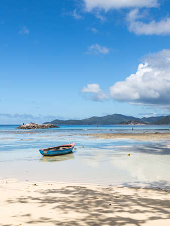 beautiful beach with coral white sand, the shade of the trees and boat on the island of La Digue, Seychellesの写真素材