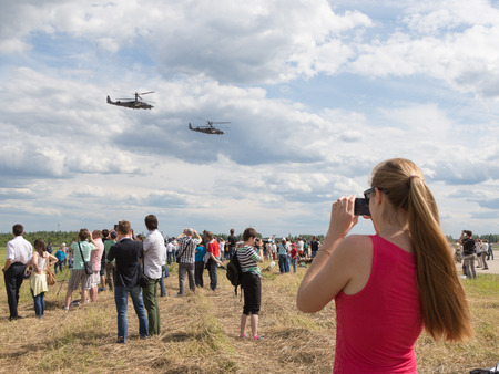 Moscow Region - June 17, 2015: A lot of people take pictures of the airfield Kubinka Airshow at the "Army 2015" and fly two military vertalet June 17, 2015, Moscow Region, Russiaのeditorial素材