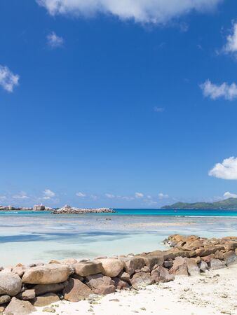 Lovely Vertical seascape with a breakwater made of stones in a clean transparent blue sea, Seychellesの写真素材