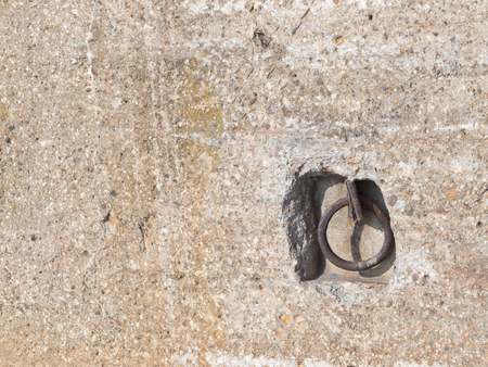 gray and brown rough old concrete wall with spots and and iron ring in the niche for tying boats on the waterfrontの写真素材
