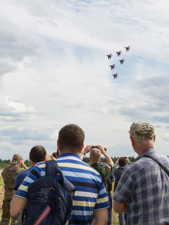 The Moscow region - 19 June 2015: Spectators take pictures of the airshow demonstration flights of military aircraft MiG-29 beautiful aerobatic team Swifts at the airfield Kubinka June 19, 2015, Moscow Region, Russiaのeditorial素材