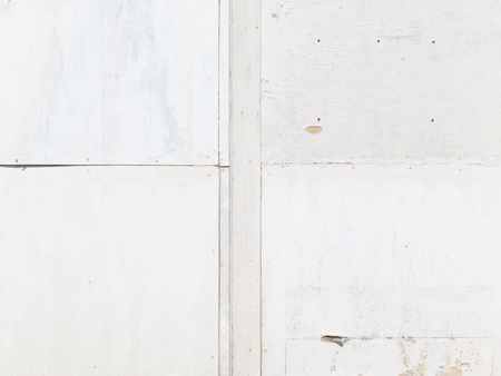 surface rough peeling old white wooden painted wall with stitches in the street