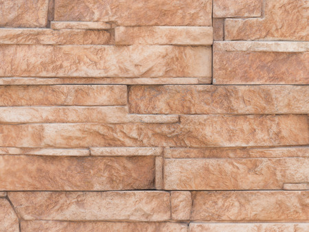 wall bright brown artificial stone facade with rough fractured surfaces, laid as a brick