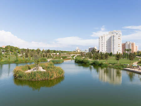 Alicante - 13 October 2015: A beautiful landscaped park with a pond, a variety of ornamental plants and water and a dirt track in a residential area of 13 October 2015, Alicante, Spainのeditorial素材