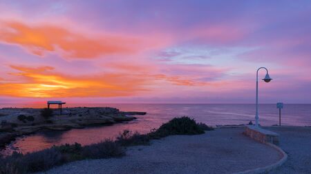 Beautiful pink sea landscape with rocky coastline of rocks and clear blue sea at dawn in the early...