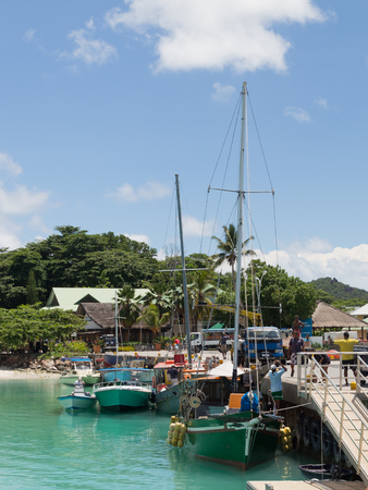 La Digue - November 10, 2014: Boats and yachts stand at the port of the island of La Digue, and people working in the port on a sunny day, November 10, 2014, the island of La Digue, Seychellesのeditorial素材