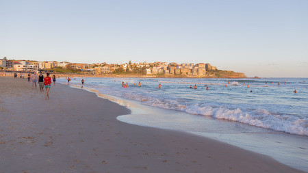 Sydney - March 1, 2016: The city beach and people swimming at sunset and yellow sunlight on urban low-rise building March 1, 2016, Sydney, Australiaのeditorial素材