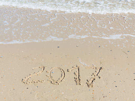 2017 inscription on a light yellow sand fines with small stones and fragments of shells on the sandy...