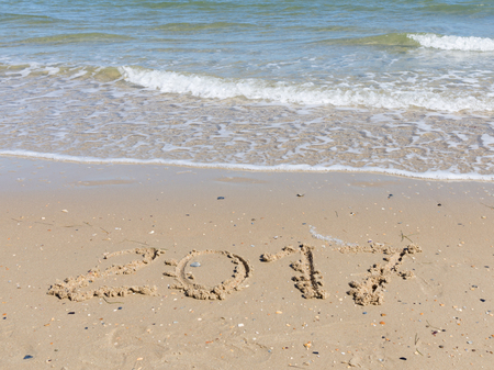 2017 inscription on a light yellow sand fines with small stones and fragments of shells on the sandy...