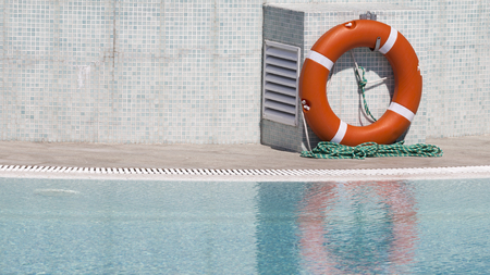 Bright orange lifebuoy by the pool with clear clear waterの写真素材