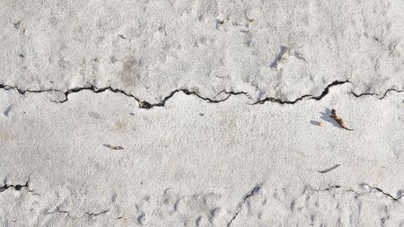 the surface of old dirty gray concrete with dark cracks and stains on the streetの写真素材