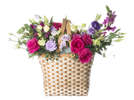 beautiful bright tender bouquet of flowers in a woven straw basket on a white isolated backgroundの写真素材