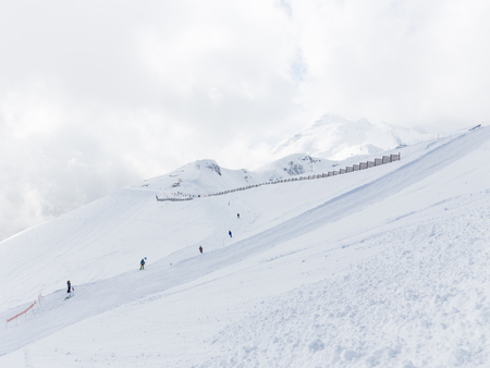 unrecognizable skiers ride on a ski slope, snow and clouds in the mountains Russia, Russiaのeditorial素材