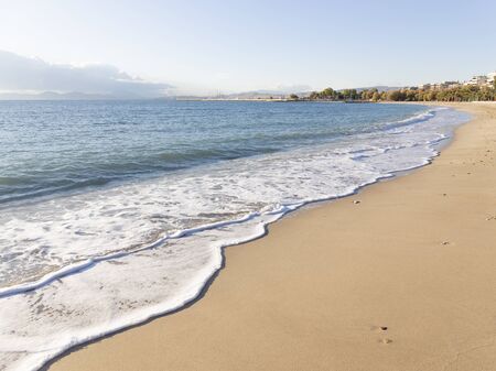 clean sandy beach and sea foam on the beach in Athens and the city in the distance, Greeceの写真素材