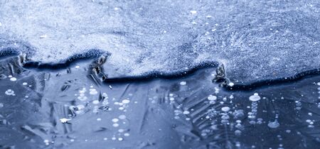 a flood of thick blue ice on thin ice on a river in cold winterの写真素材