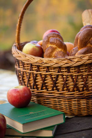 Basket with buns and apples, pumpkins and books on the background of an autumn landscapeの写真素材