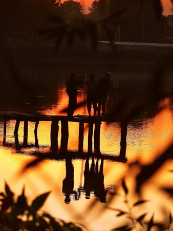 fishermen at the pier on the lake background sunsetの写真素材