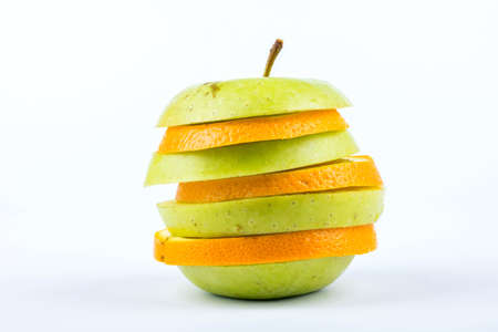 Apple and orange slices stacked in one piece of fruit on a white の写真素材
