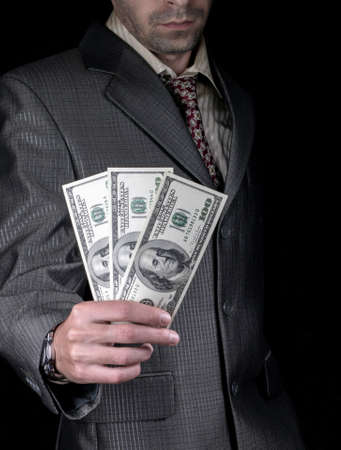 Businessman holding money for a hundred dollars on a black の写真素材