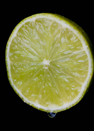 Sliced ââlime with dripping juice on black backgroundの写真素材